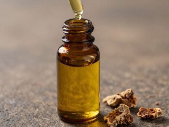 Bottle of golden frankincense oil with resin pieces.
